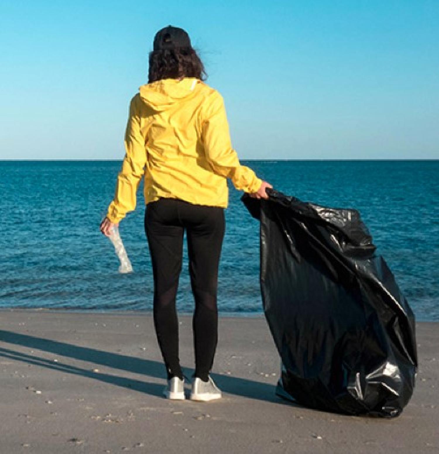 woman picking up trash on the beach