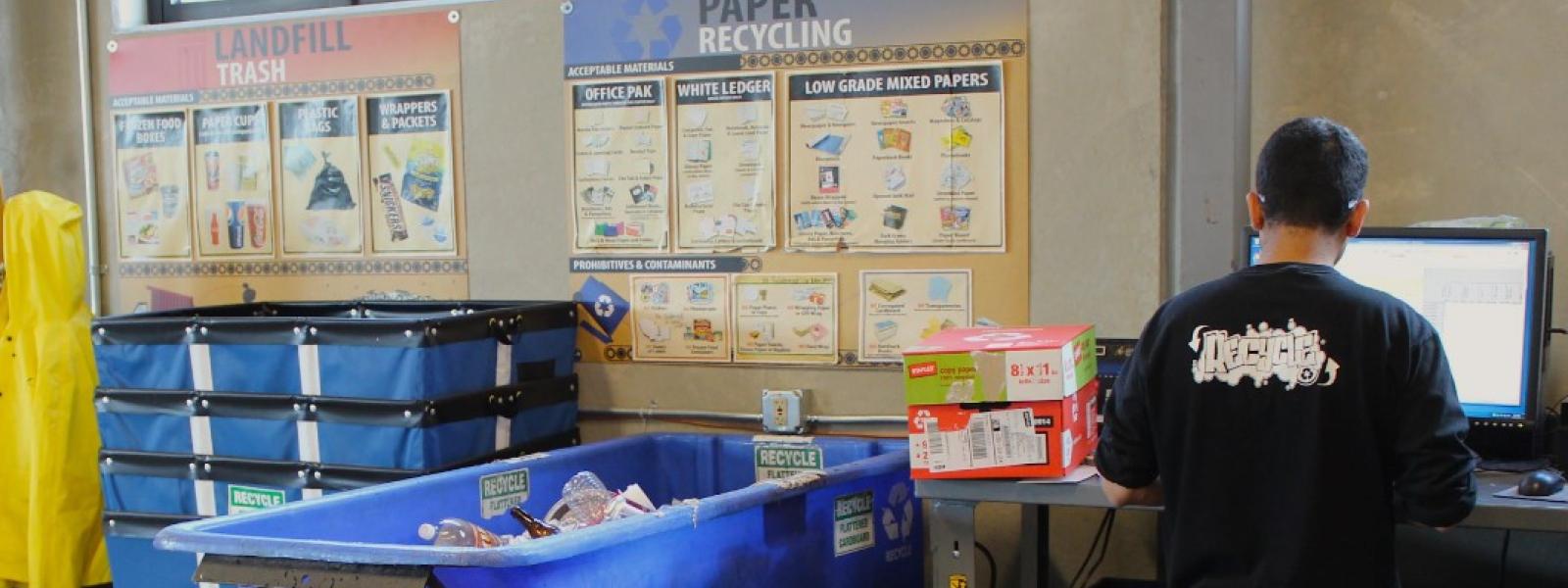 A student worker weighs a full tip cart of recycling
