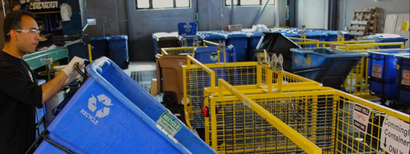 A student worker dumps the contents of a full tip cart into a "roll off" bin