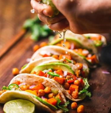 person squeezing a lime onto tacos