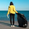 woman picking up trash on the beach