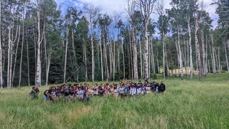 Students gathered in a field, trees in background