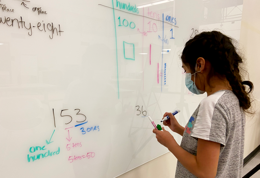 Student solving a math problem on the whiteboard