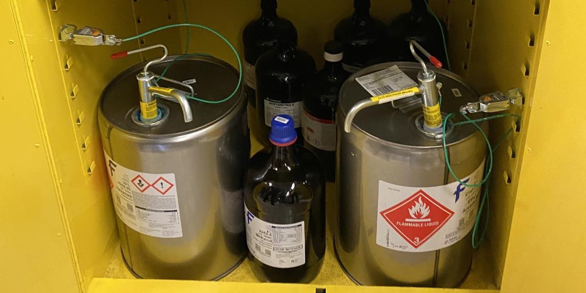A flammable storage cabinet filled with chemical containers.
