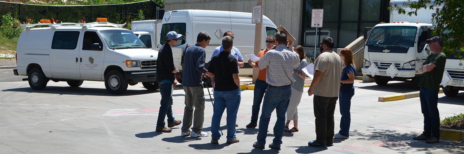 EH&S employees talking in parking lot with department vehicles behind them