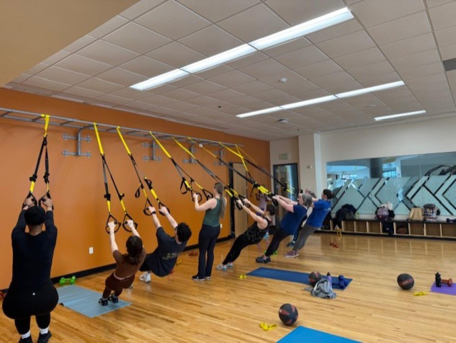 A group of people doing a TRX workout class