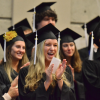 Group of female students in their caps & gowns and clapping at graduation