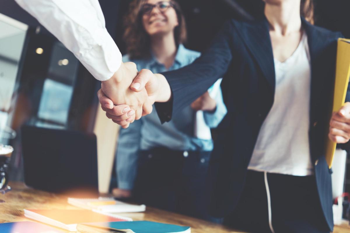 Two people shaking hands over a desk
