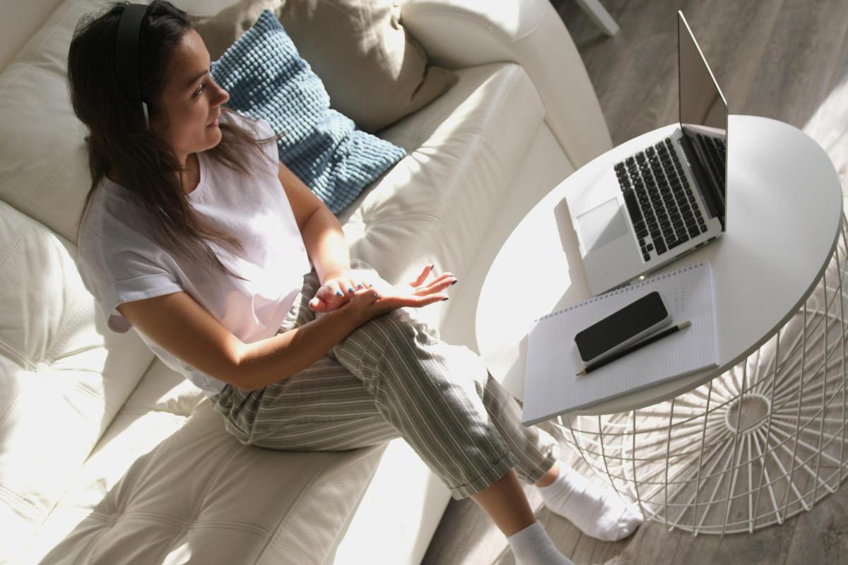 A woman participating in a virtual meeting while sitting on her couch