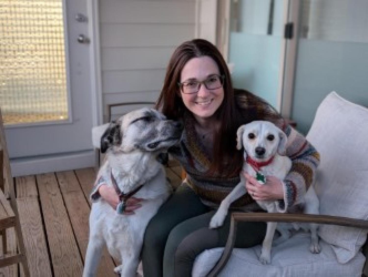 Arielle sits with her arms around her two dogs