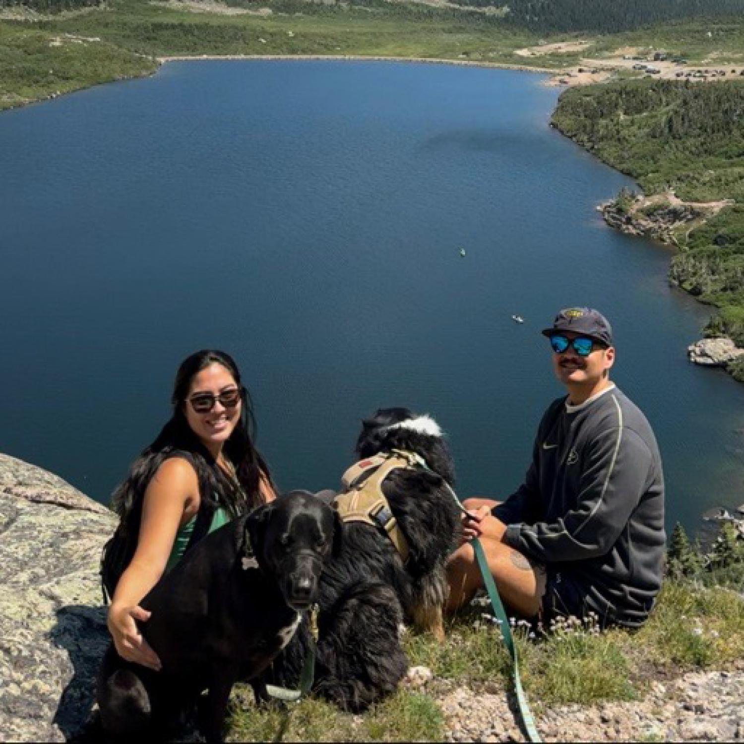 Maile, Shane and their dogs enjoy a lake view during a hike