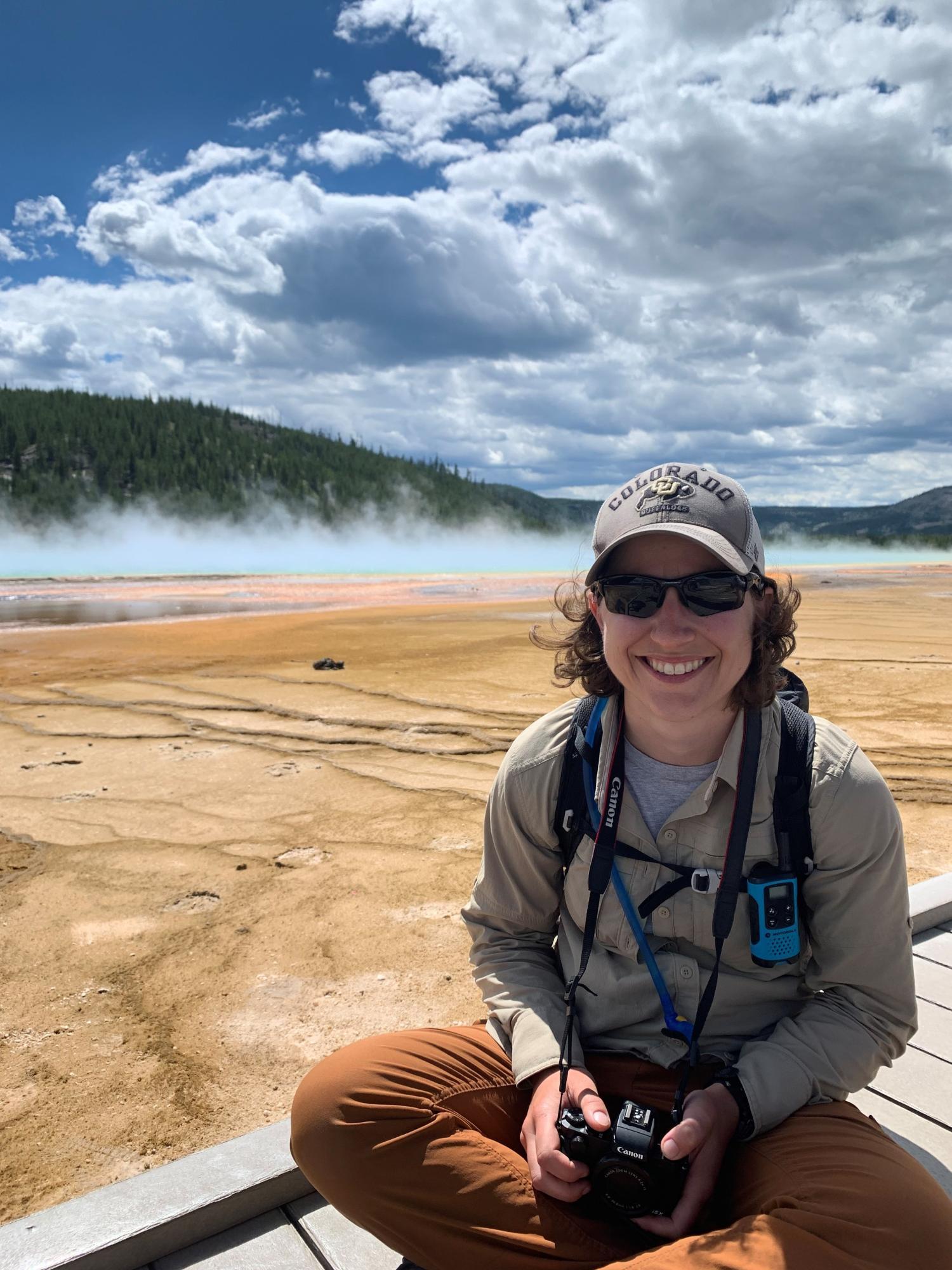Victoria sits on the boardwalk next to a hot spring in Yellowstone