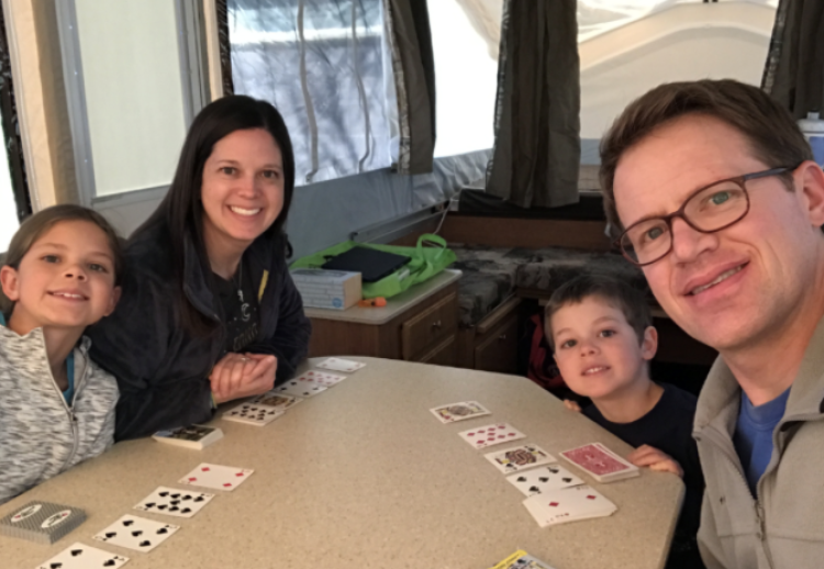 Nick and his family play cards in their camping trailer
