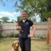 Rowie in her engineering polo, holding a chicken with her dog sitting at her feet