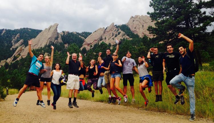New Balsells Fellows on a welcome hike, jumping, with Flatirons in the background.