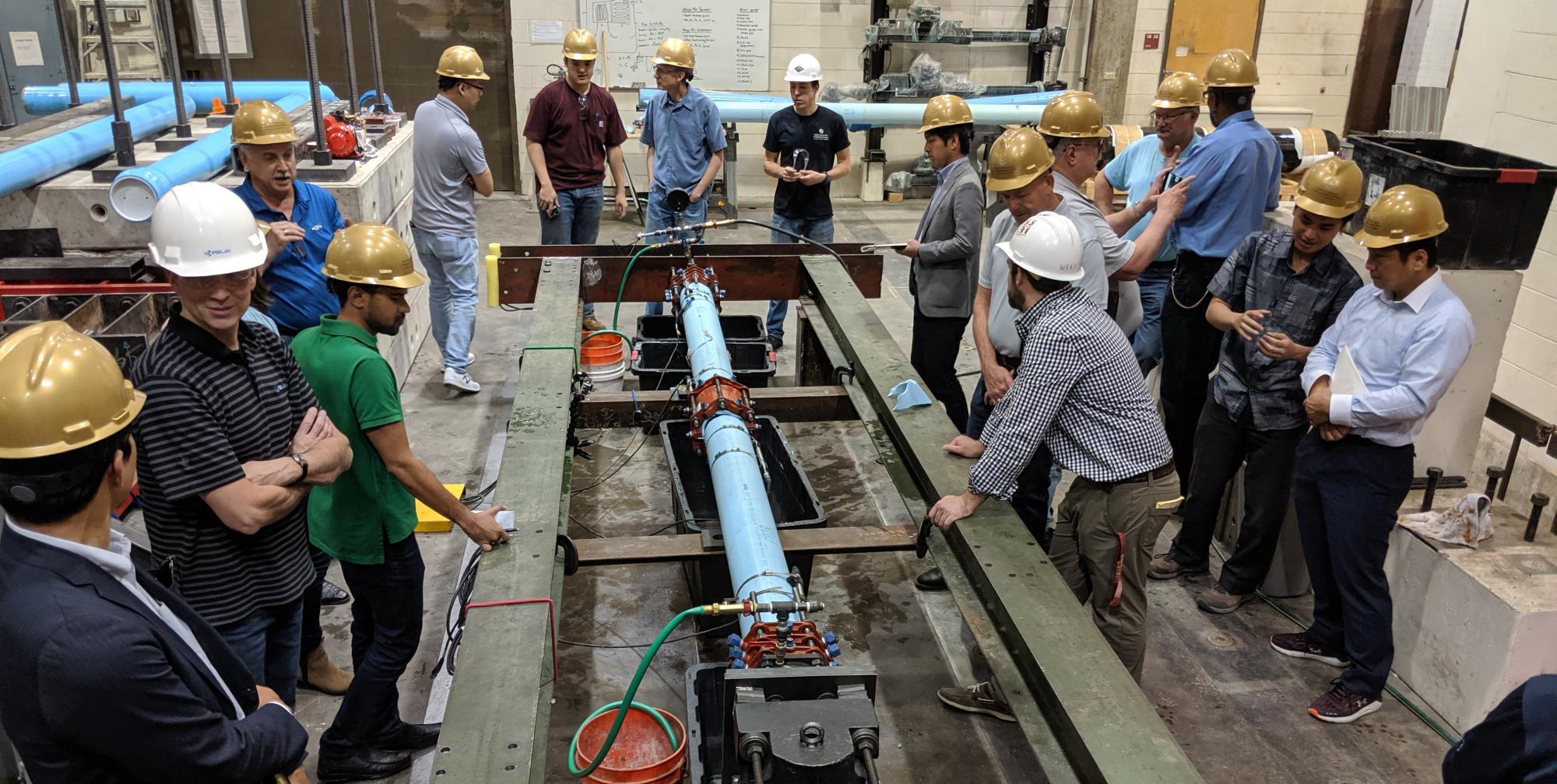 A group of water experts gather around the seismic testing equipment in the CIEST lab. 