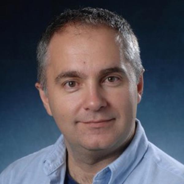 White man with greying dark hair wearing blue button up shirt