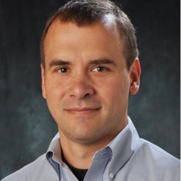 white man with receding dark hair wearing a blue button up shirt