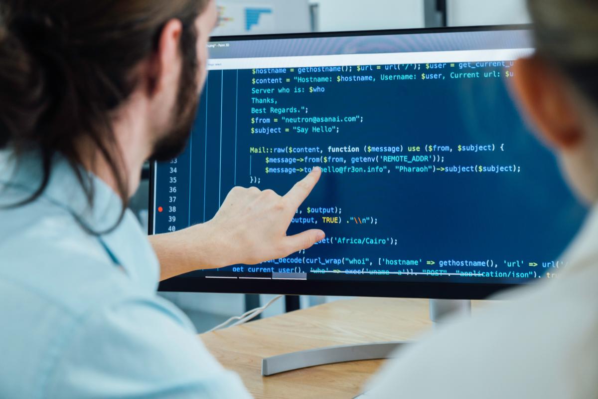 Two people working on code on a computer screen