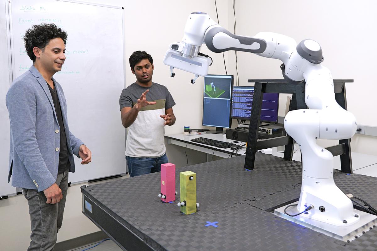 Researcheres in a lab testing a robotic arm