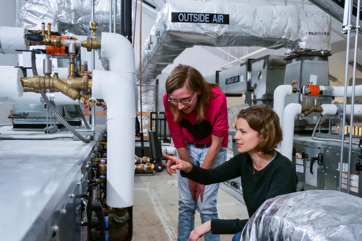 Two students checking the temperature and pressure settings for a rooftop HVAC unit in the Larson Laboratory.