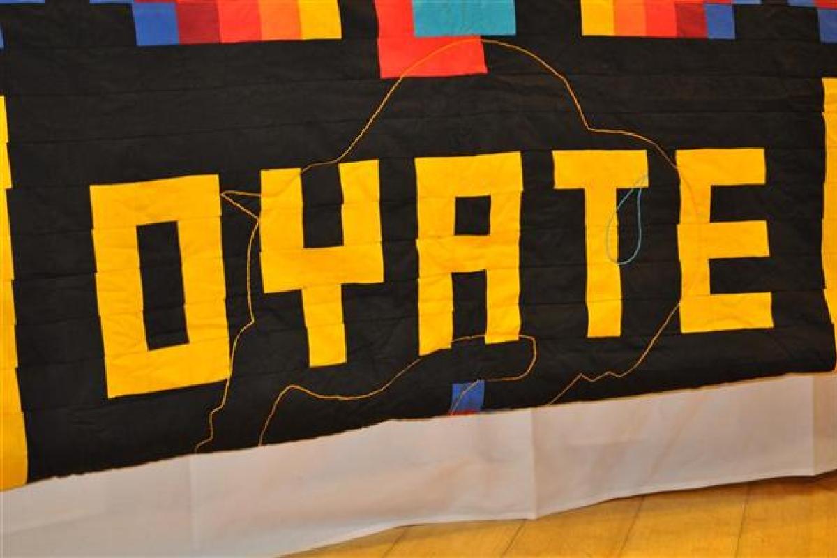 Quilted image of word "OYÁTE" in yellow