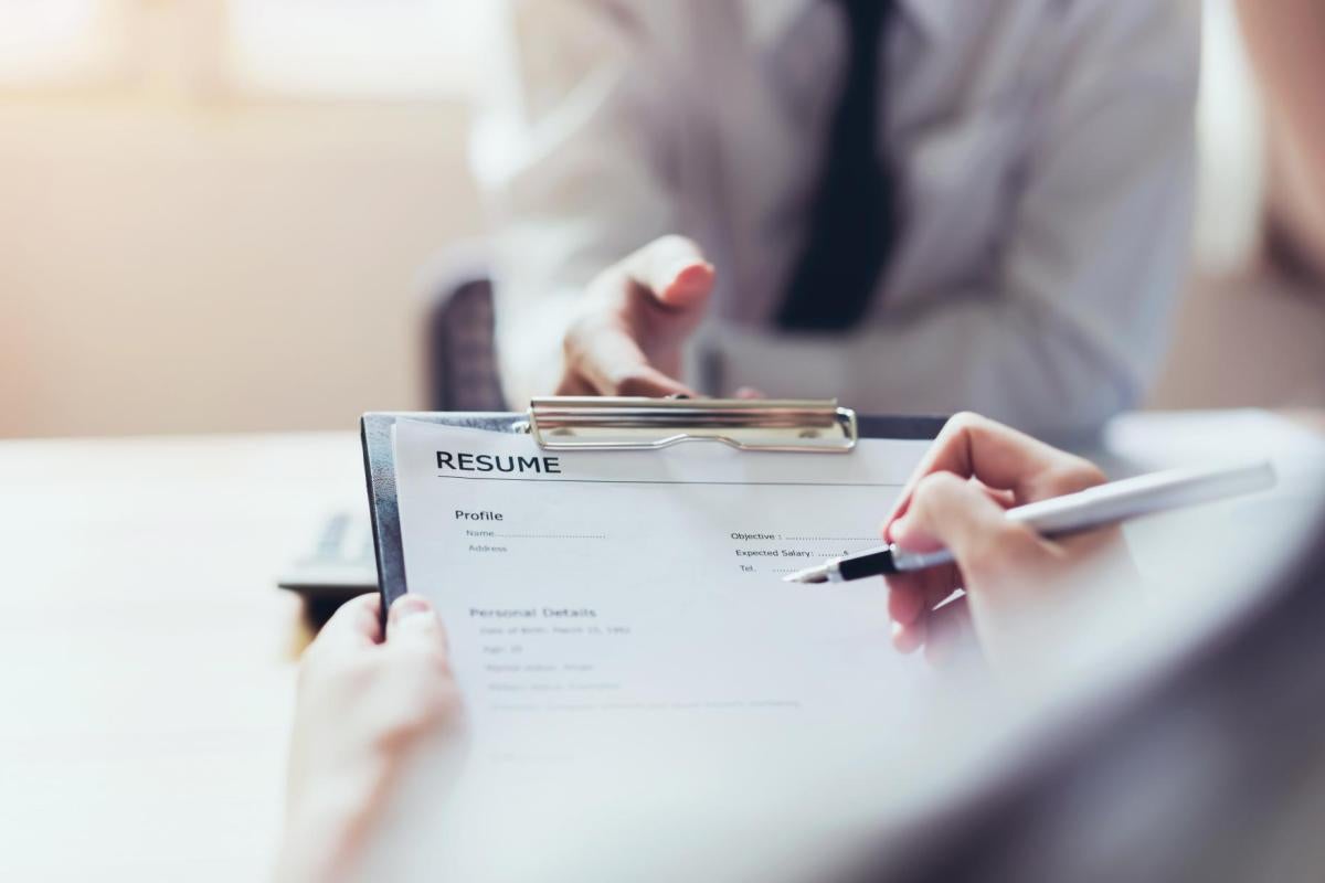 A close-up of hands holding a resume during an interview.