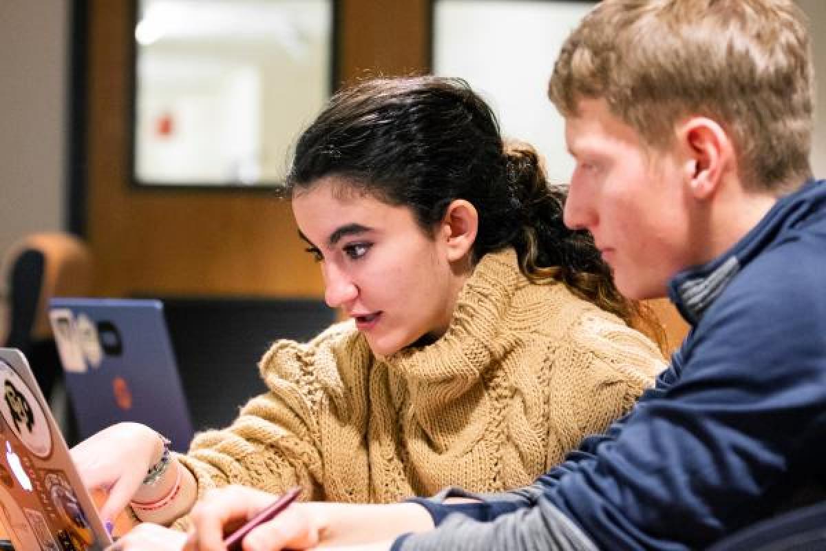 two people look intently at a computer