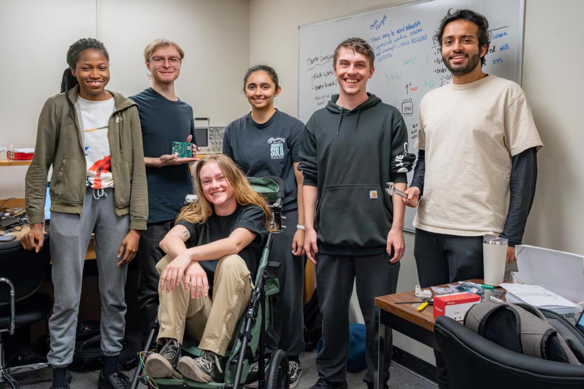 A six-person teams shows off an assistive mobility device in the ECEE capstone lab