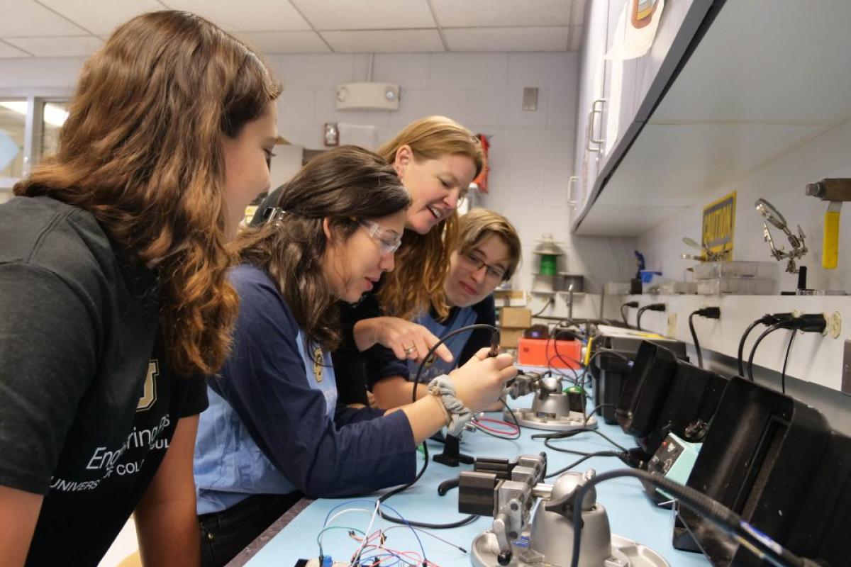 professor guiding students working on a circuits project