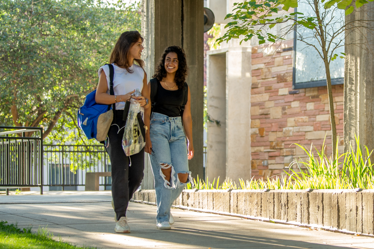 Two female students walking and chatting happily on campus