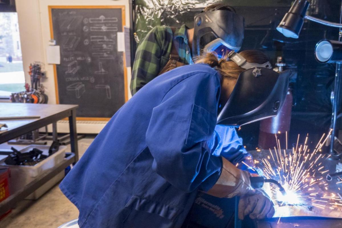 Person with long hair welds with sparks flying