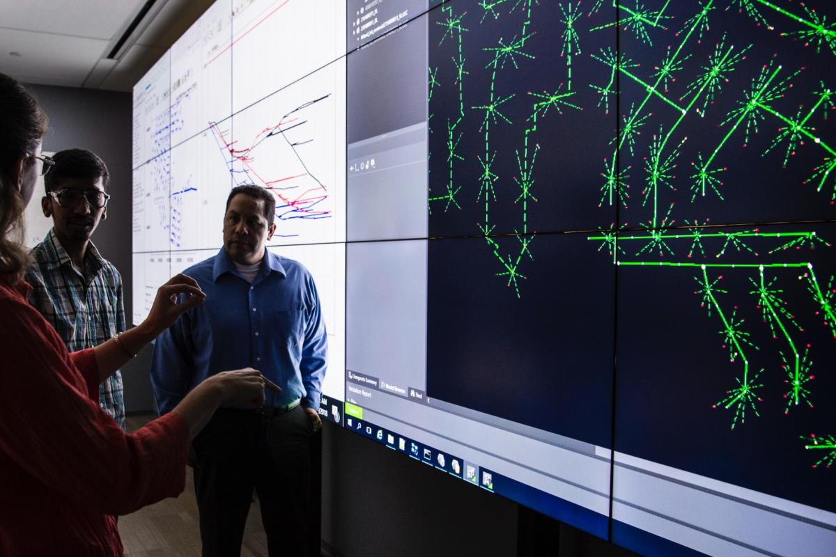 group of people discussing simulation displayed on screen