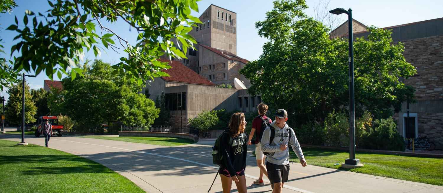 Students walking past the Engineering Center building on a sunny, summer day