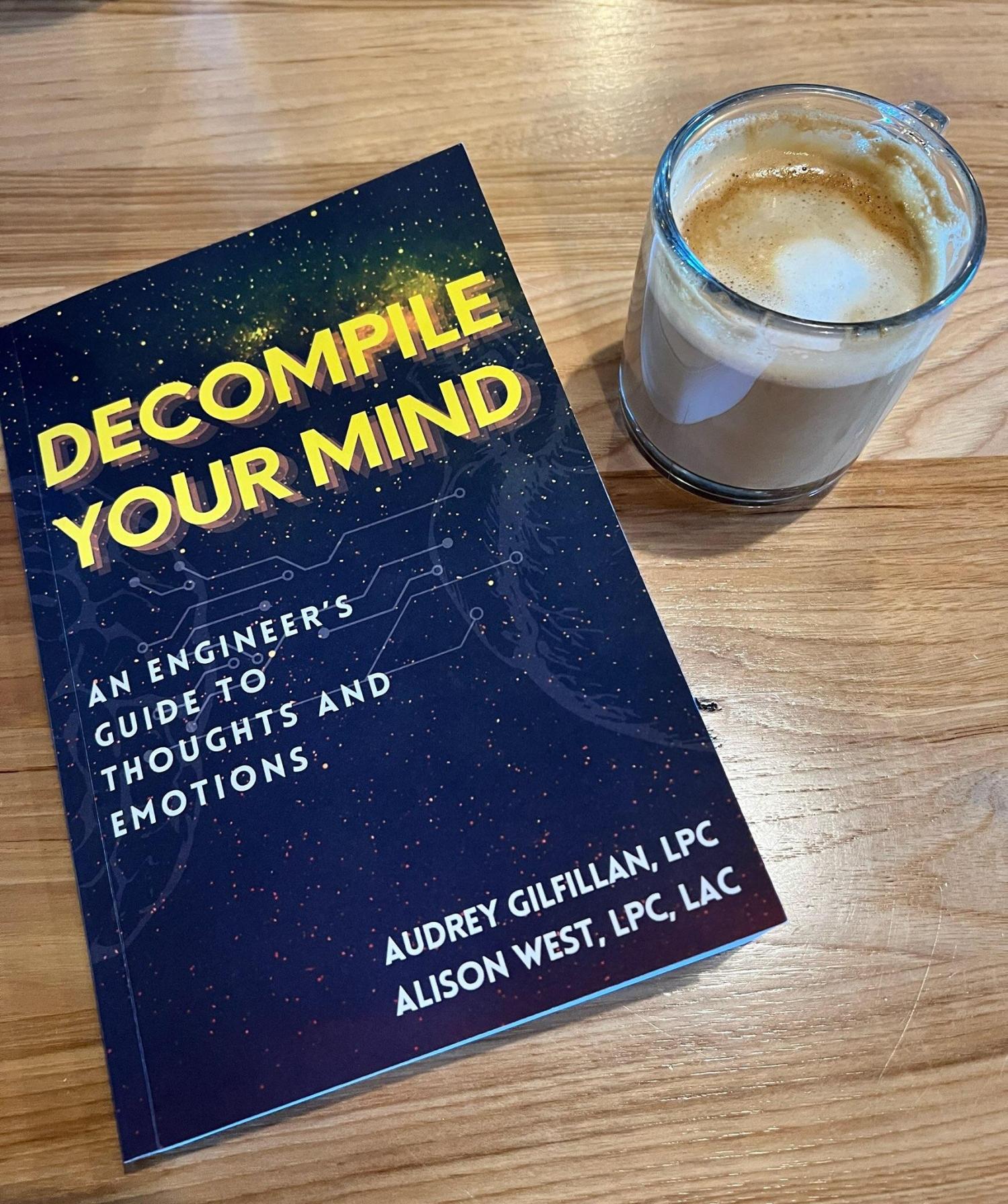 A copy of Decompile Your Mind next to a cup of coffee