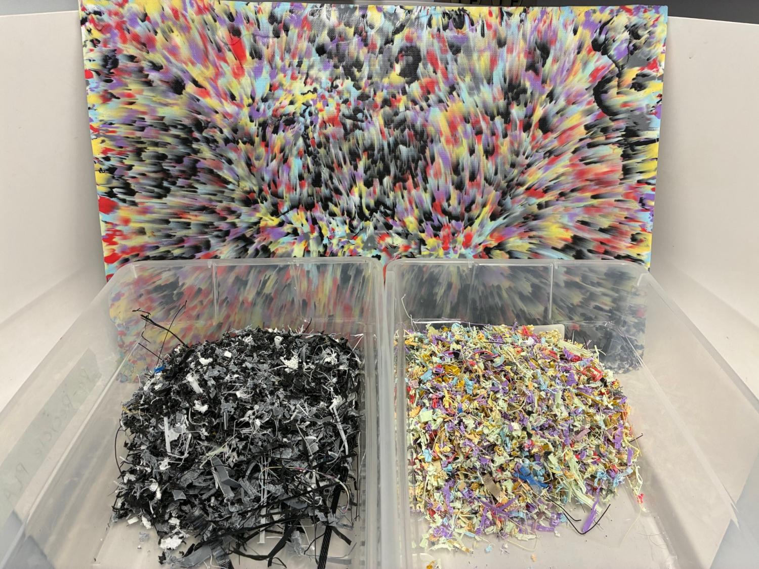 Two container of PLA fragments, with a finished pressed sheet behind them