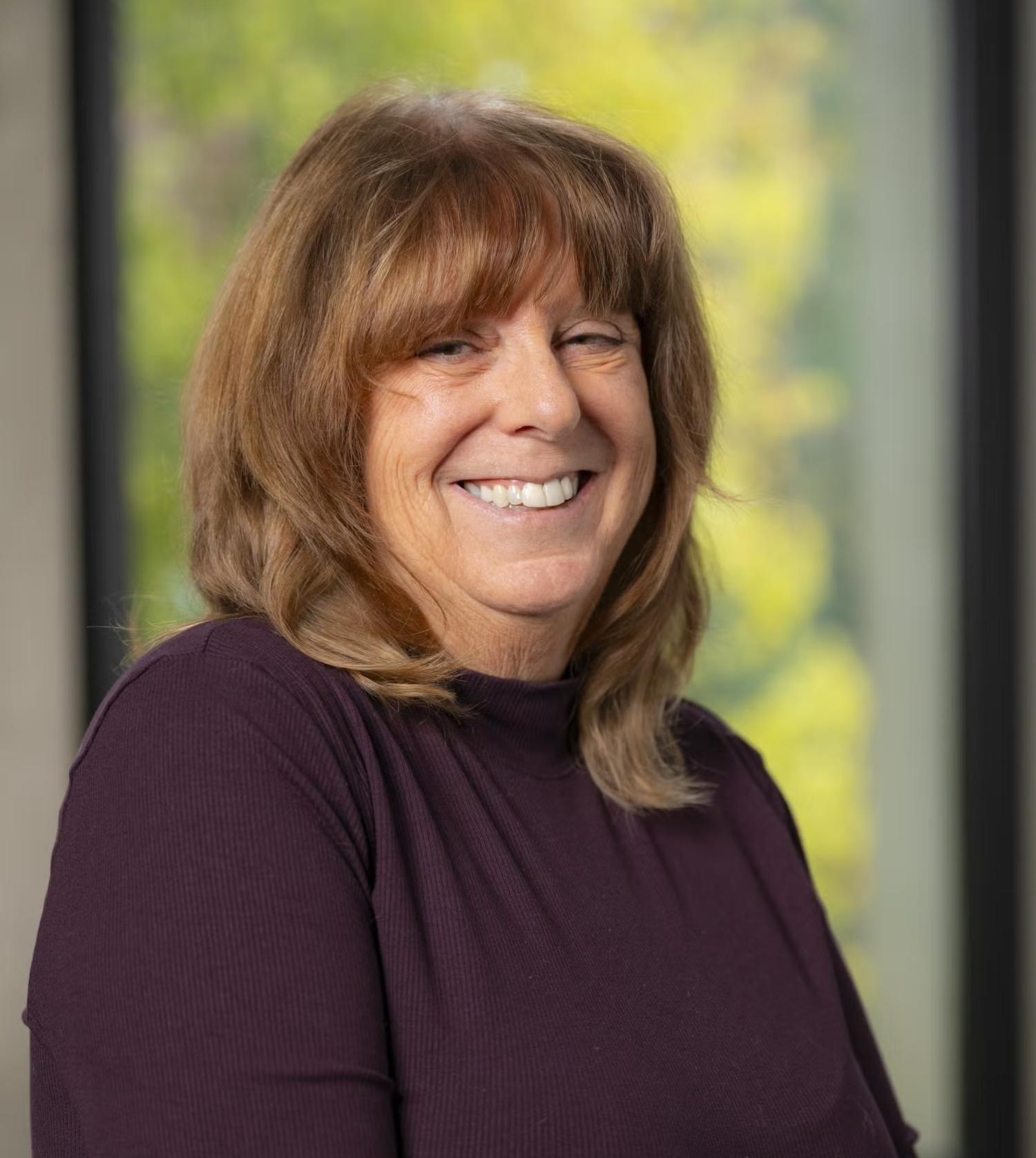 Susan Glairon with blurred trees in the background.