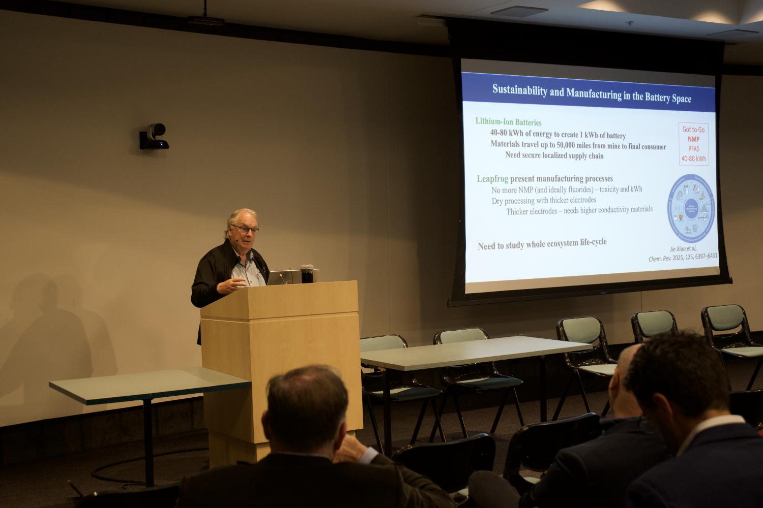 A person at a podium giving a presentation in front of a seated crowd