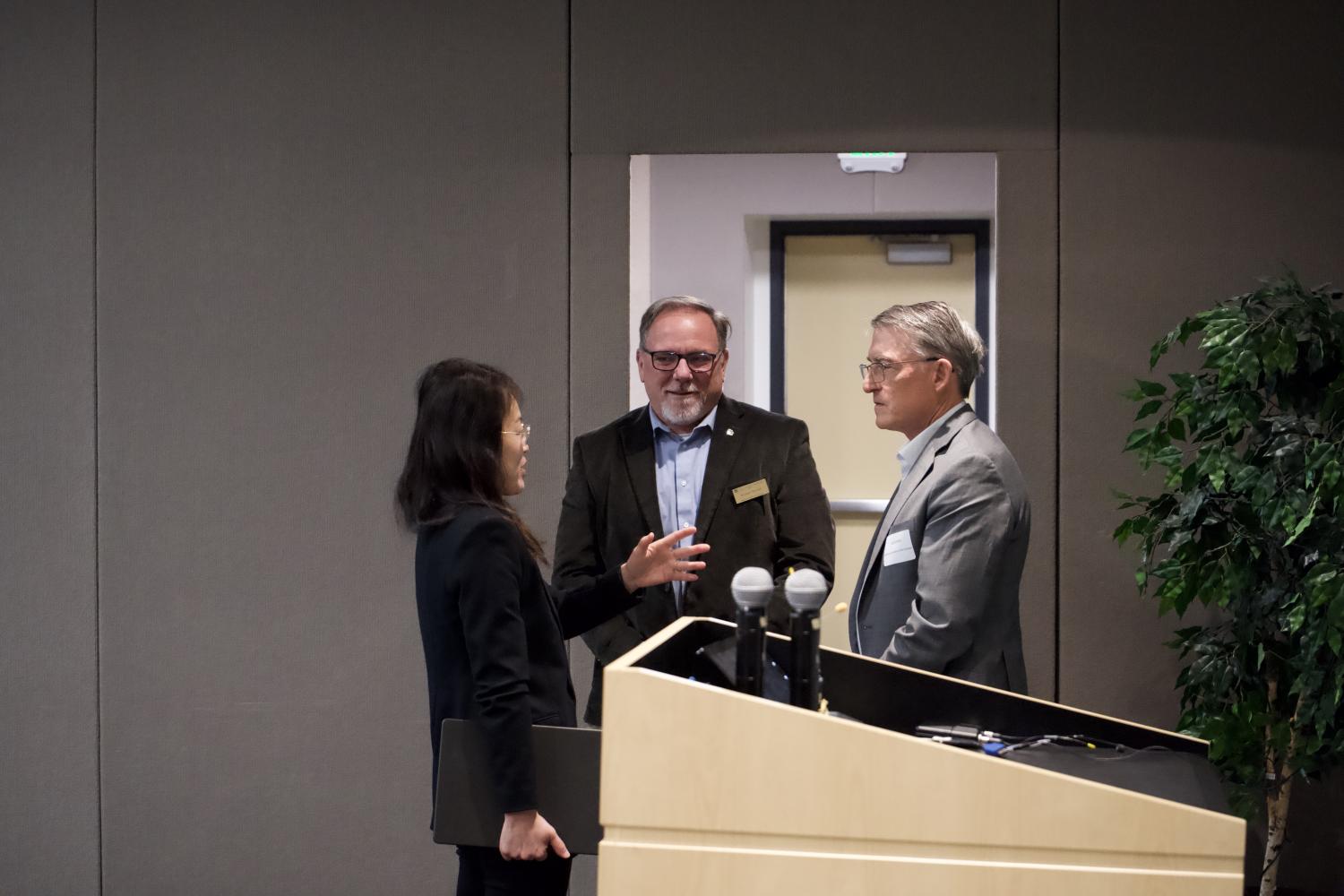 Three people conversing with each other at a conference
