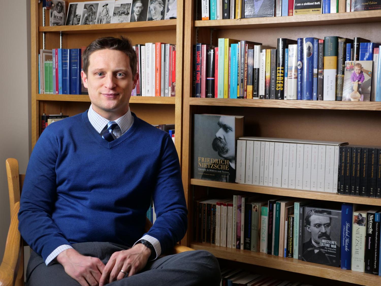 Shilo Brooks sits beside bookshelf