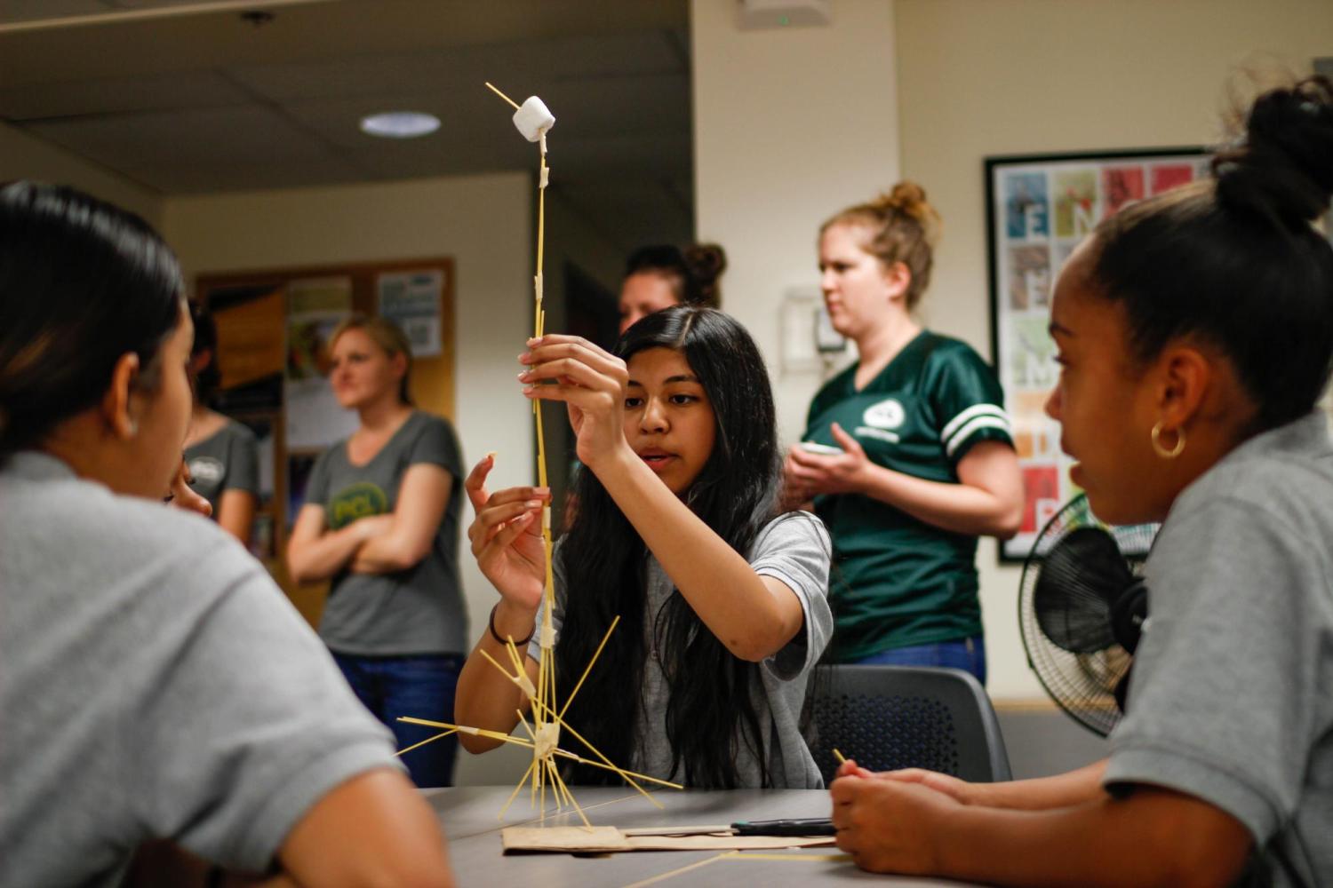 female middle school students tackle pasta and marshmallow challenge