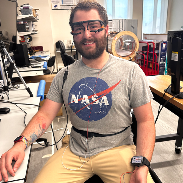 Liam Masias testing lab equipment on his face and wrists while wearing a NASA tshirt