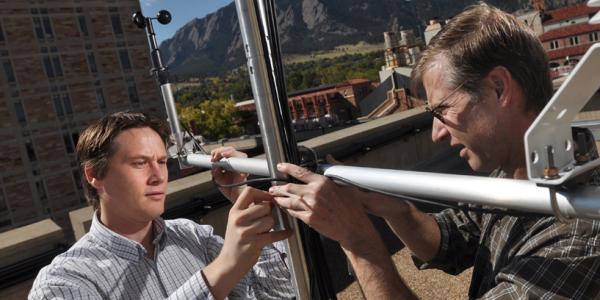 Two people work to secure a metal pole