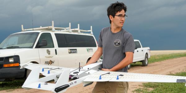 student in the field with a drone