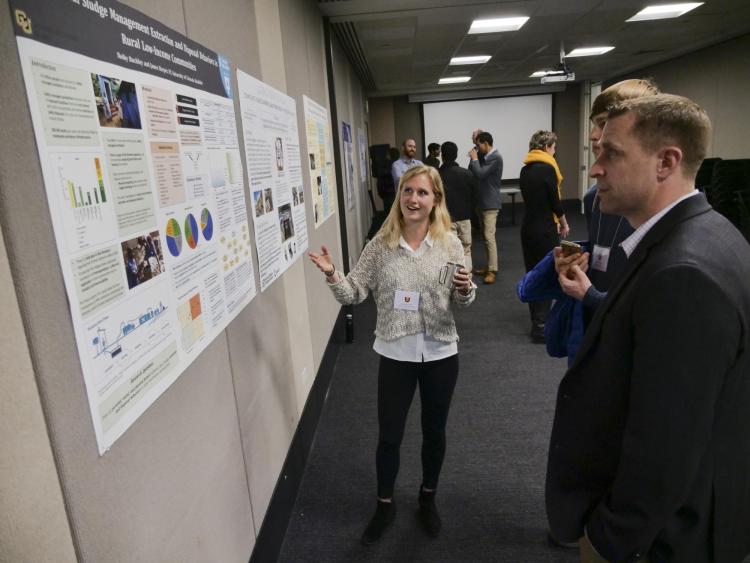 A WASH Symposium presenter discusses her project with award ceremony attendees.