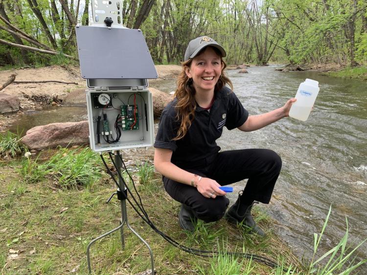 Emily Bedell collecting a sample from a river