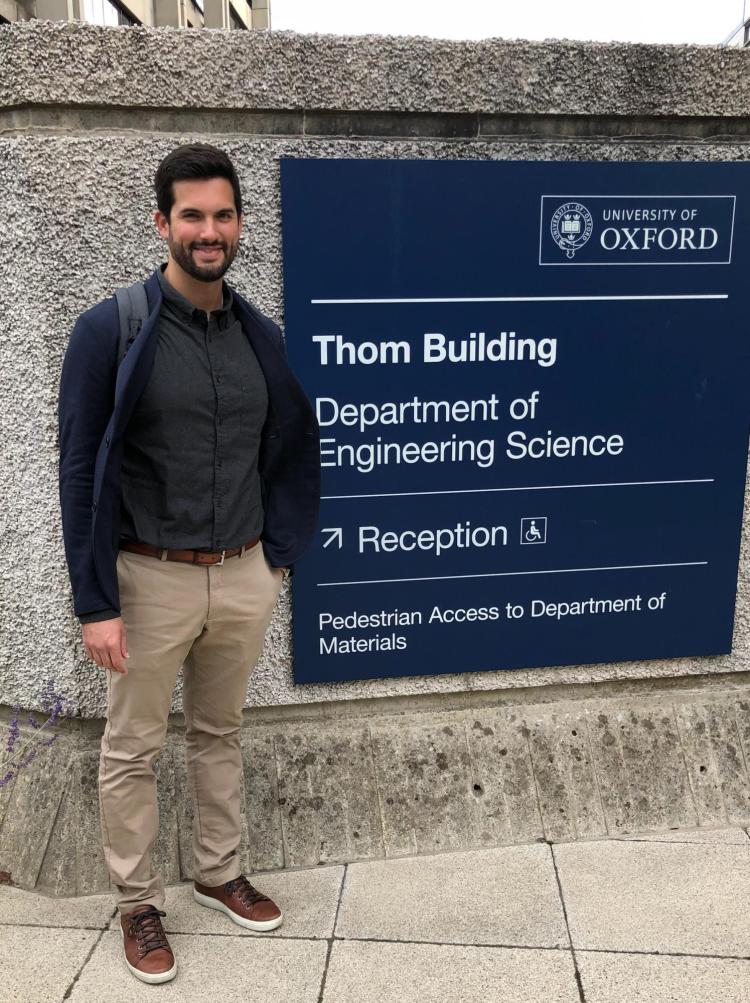 Alec Thomas standing next to a sign at Oxford 