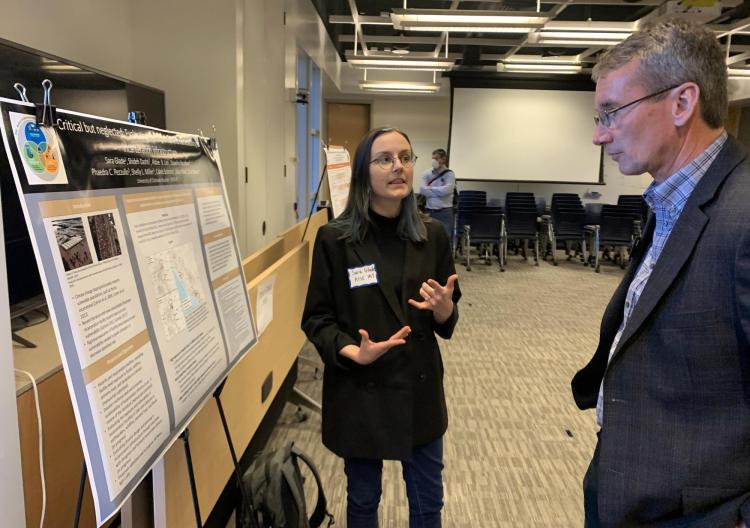 A research presents their poster to Acting Dean Keith Molenaar