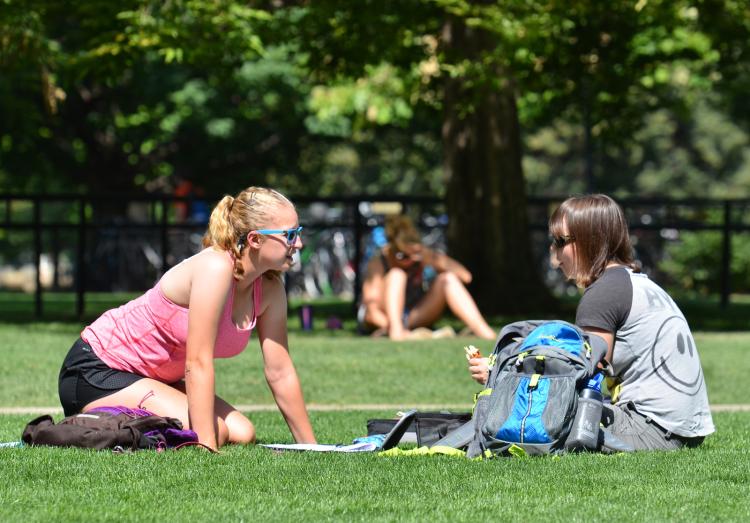 Students sitting on grass on campus 