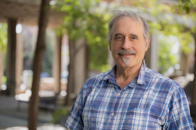 Professor Al Bovik standing in front of a courtyard surrounded by trees.